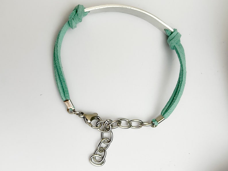 May include: A green suede bracelet with a silver metal band and a silver clasp.