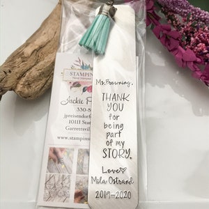 May include: A silver bookmark with a turquoise tassel. The bookmark has the text "Ms. Browning, THANK YOU for being part of my STORY. Love, Mila Ostrand 2019-2020" engraved on it.