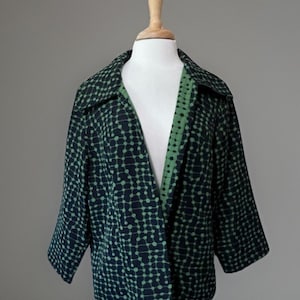 May include: A dark navy blue jacket featuring a repeating pattern of light green dots connected by thin lines. The jacket has a wide collar, three-quarter length sleeves, and an open front design with a contrasting light green inner lining.