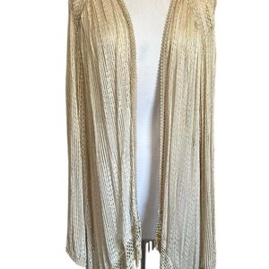 Può includere: Un cardigan a maniche lunghe aperto sul davanti, realizzato in un tessuto color beige chiaro con riflessi metallici. Il capo presenta una trama a coste verticali, un delicato bordo all'uncinetto e un orlo sfrangiato con motivo traforato.