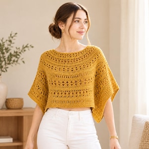 Puede incluir: Un top de ganchillo color amarillo mostaza con un amplio escote barco, mangas cortas acampanadas y un patrón calado repetitivo en todo el cuerpo. La prenda es corta a la cintura y se combina con pantalones vaqueros blancos con cierre de botón.