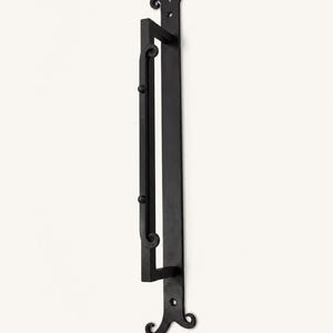 May include: A matte black metal door handle featuring a long, vertical rectangular backplate with decorative scrolled ends. The handle itself is a straight bar with two small spherical accents and curved ends, mounted to the backplate.