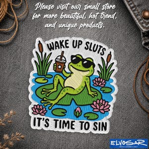 May include: An embroidered patch featuring a green frog wearing black sunglasses, sitting on a lily pad in blue water with pink lotus flowers and cattails. The text reads WAKE UP SLUTS IT'S TIME TO SIN, with the frog holding a brown coffee cup.
