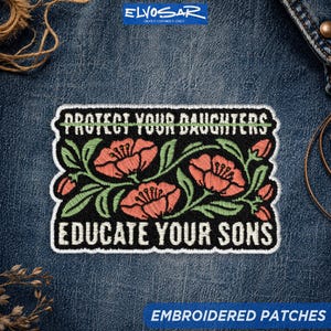 May include: A rectangular embroidered patch on blue denim fabric featuring the text PROTECT YOUR DAUGHTERS and EDUCATE YOUR SONS in white capital letters, with a central design of three coral-pink flowers and green leaves on a black background.