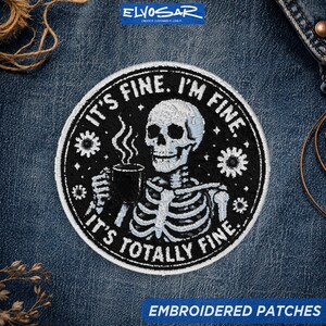 May include: A circular embroidered patch featuring a white skeleton holding a steaming black mug. The text reads IT'S FINE. I'M FINE. IT'S TOTALLY FINE. The design includes small white flower accents on a black background with a white border.