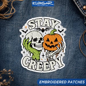 May include: An embroidered patch featuring a white skull held by a green hand and an orange jack-o'-lantern held by a skeletal hand. The text STAY CREEPY is arched above and below the central design, accented by small bats and stars.