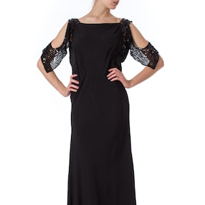 May include: A black floor-length gown with a scoop neck and cold shoulder design. The sleeves are embellished with sequins.