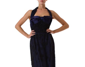May include: A navy blue halter dress with a beaded bodice and a flowing skirt. The dress has a satin bow at the neckline.