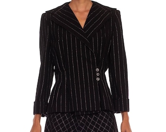 May include: A black and white pinstripe suit featuring a blazer and skirt. The blazer has a notched collar, long sleeves, and decorative buttons. The skirt has a diamond pattern.