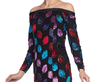 Puede incluir: Vestido de hombros descubiertos con mangas largas, con fondo negro y un estampado de hojas de colores. Las hojas son de terciopelo y tienen un acabado brillante e iridiscente.