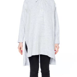 Puede incluir: Una camisa de lino azul claro de manga larga con cuello abotonado y un dobladillo alto-bajo.