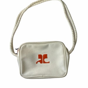 May include: A white canvas crossbody bag with a rope strap and an orange logo.