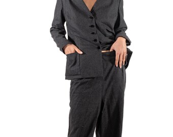Op de afbeelding: Een antracietgrijs pak met een blazer met een revers en knoopsluiting, gecombineerd met een broek met wijde pijpen. De blazer heeft voorzakken. Het pak is gemaakt van een textuurstof en biedt een klassieke en professionele uitstraling.
