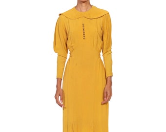 May include: A mustard yellow midi dress with a Peter Pan collar, long sleeves, and a button closure down the front. The dress has a fitted bodice and a flowing skirt.