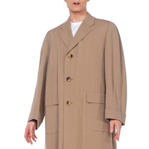May include: A long, tan, single-breasted coat with four buttons and two large pockets.
