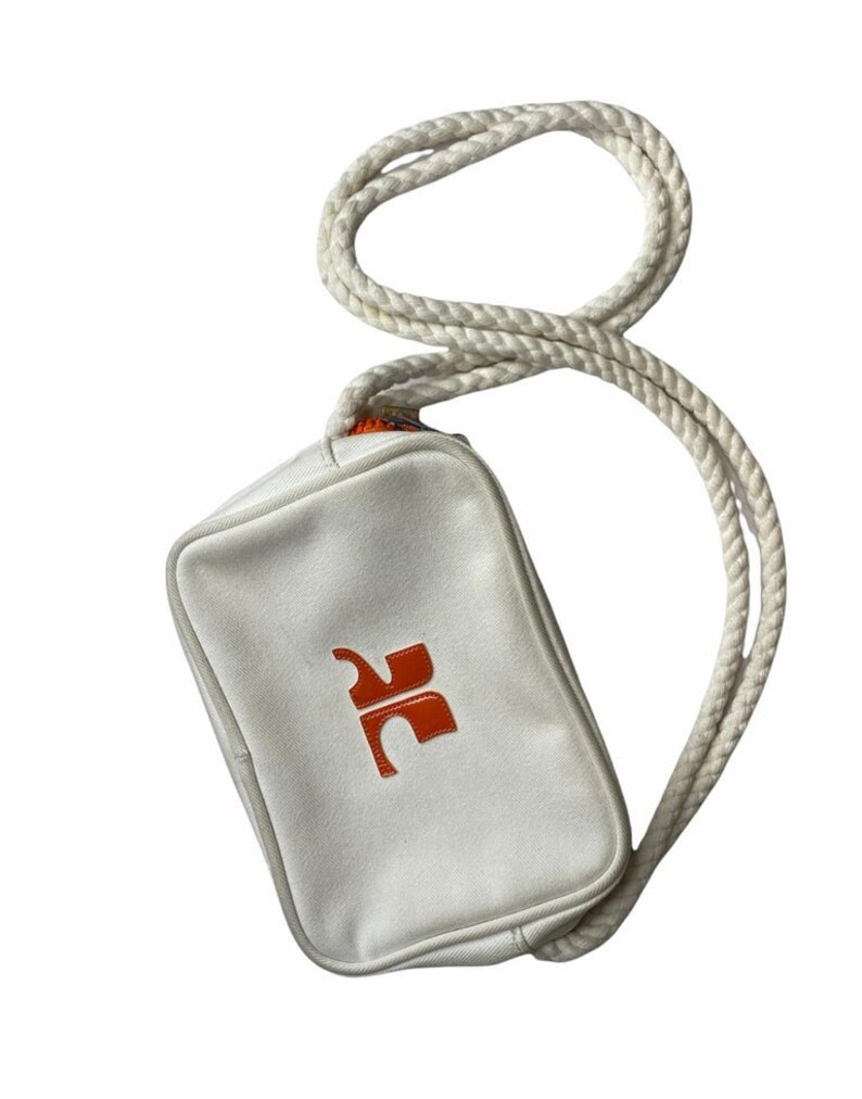 May include: A white canvas crossbody bag with a rope strap and an orange logo.