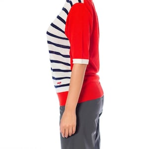 May include: A red and white striped short-sleeved sweater with a red logo on the front. The sweater is made of a soft, comfortable material.