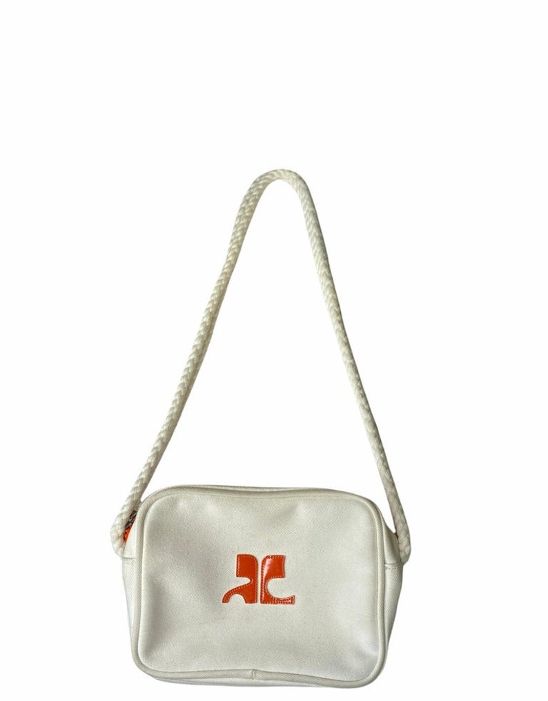 May include: A white canvas crossbody bag with a rope strap and an orange logo.