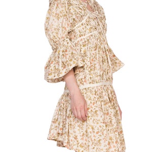 May include: A white dress with a floral print and a tie at the neck. The dress has a ruffled hem and 3/4 sleeves.