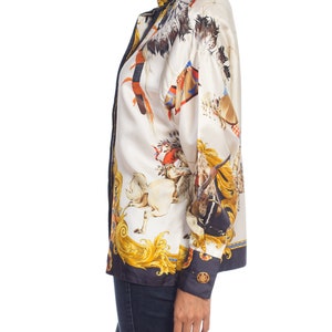 May include: A white silk blouse with a colorful print of horses and riders. The print features gold accents and a black background. The blouse has a long sleeve and a button-up front.