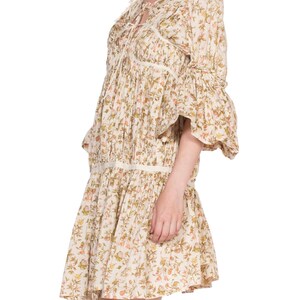 May include: A white floral print mini dress with a tie at the neckline and 3/4 sleeves. The dress has a gathered skirt and a fitted bodice.
