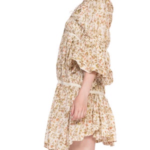 May include: A white floral print mini dress with a gathered skirt and 3/4 sleeves. The dress has a V-neckline and a tie at the neckline.