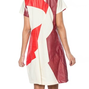 Puede incluir: Vestido de manga corta con dise&ntilde;o geom&eacute;trico. El vestido presenta un patchwork de paneles rojos, crema y burdeos. El vestido tiene un corte sencillo y recto y parece estar hecho de un material texturizado.