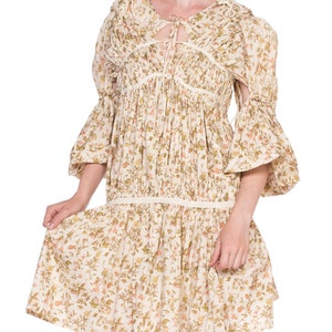 May include: A white floral print dress with a tie at the neckline and 3/4 sleeves. The dress has a gathered skirt and a relaxed fit.