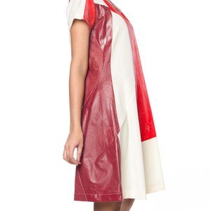 Puede incluir: Un vestido con bloques de color que presenta un dise&ntilde;o audaz con paneles rojos, blancos y burdeos. El vestido tiene mangas cortas y un escote en V. Los paneles burdeos tienen una apariencia texturizada similar al cuero, agregando un elemento &uacute;nico a la prenda.