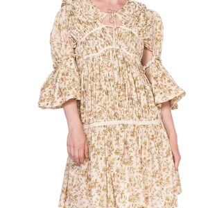 May include: A white floral print dress with a tie at the neckline and bell sleeves. The dress has a gathered skirt and a lace trim.