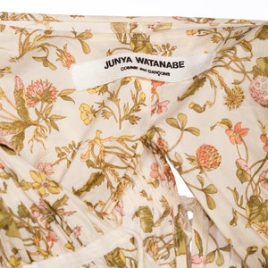 May include: A white cotton dress with a floral print featuring a Junya Watanabe Comme des Gar&ccedil;ons label.