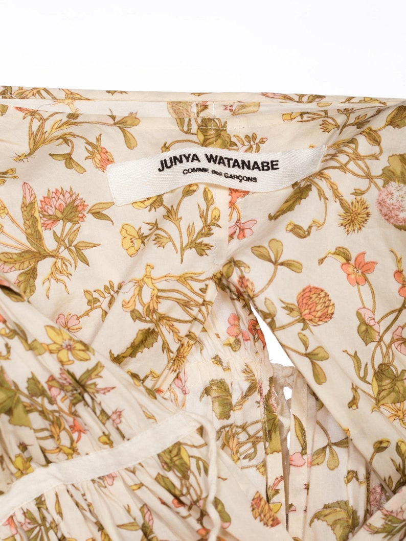 May include: A white cotton dress with a floral print featuring a Junya Watanabe Comme des Gar&ccedil;ons label.