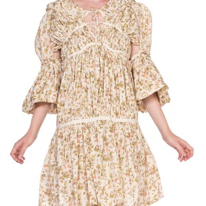 May include: A white floral print dress with a tie at the neckline and bell sleeves. The dress has a gathered skirt and a relaxed fit.