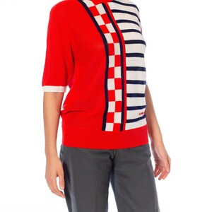 May include: Red, white, and blue striped and checkered knit sweater with short sleeves.