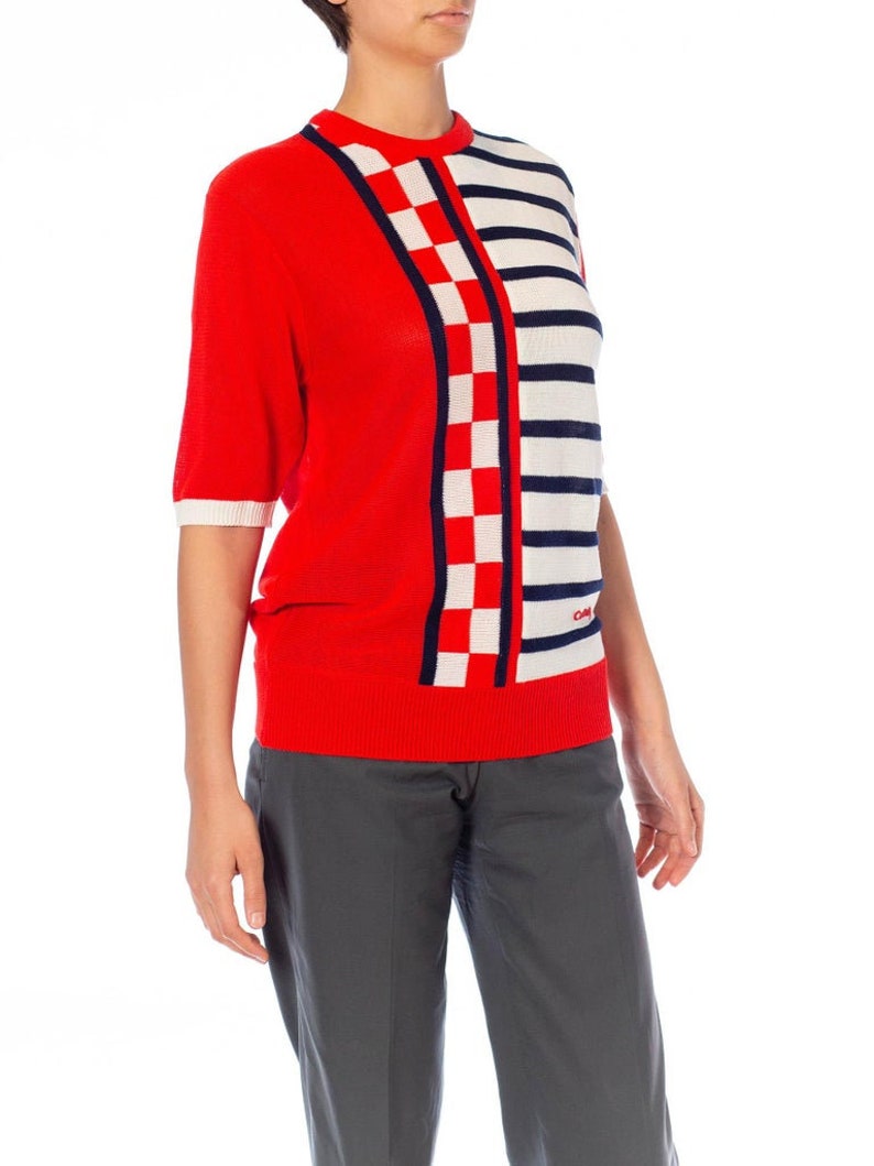 May include: Red, white, and blue striped and checkered knit sweater with short sleeves.