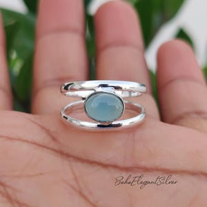May include: A silver ring featuring a double band design with a central oval-shaped light blue gemstone. The metal has a polished finish, and the text BohoElegantSilver is visible in the bottom right corner of the image.