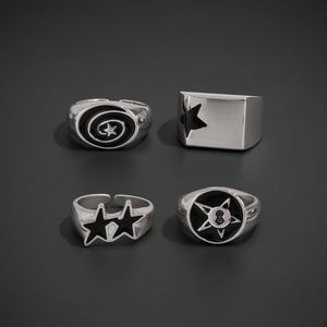 Peut inclure: Un ensemble de quatre bagues argentées avec des détails en émail noir. Une bague présente un motif en spirale avec une étoile, une est un anneau rectangulaire avec une étoile découpée, une comporte deux étoiles reliées et une affiche une étoile avec un huit.