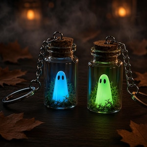Peut inclure: Deux porte-clés en forme de bouteille en verre contenant des fantômes miniatures lumineux. Un fantôme émet une lumière bleue vive, tandis que l'autre brille en vert. Chaque bouteille est scellée par un bouchon en liège et contient de la mousse.
