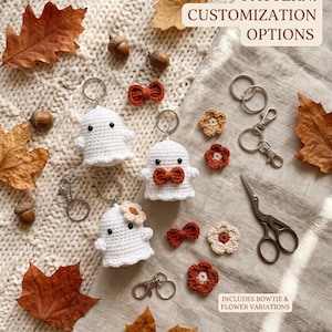 Può includere: Tre portachiavi a forma di fantasma realizzati all'uncinetto in bianco con occhi neri, dotati di accessori personalizzabili tra cui piccoli fiocchi arancioni e fiori beige o arancioni. Il set include anelli portachiavi e forbici.