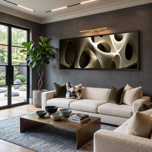 May include: A rectangular wall art piece featuring an abstract, beige, organic, porous structure with deep shadows, mounted above a cream-coloured sofa with various throw pillows, a wooden coffee table, and a large potted fiddle leaf fig plant.