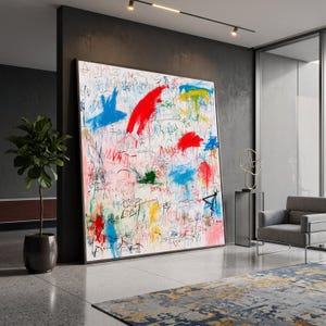 May include: A large rectangular wall art piece featuring an abstract composition with chaotic scribbles, energetic brushstrokes, and vibrant splashes of red, blue, yellow, and green paint on a white background, framed in a thin dark border.