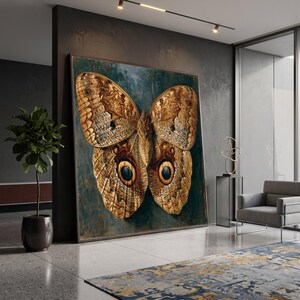 May include: A large rectangular wall art piece featuring a detailed illustration of a brown butterfly with prominent circular eyespots on its lower wings. The butterfly is set against a dark, textured teal background with visible brushstroke details.