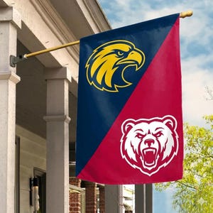 May include: A vertical house flag divided diagonally into a dark blue section and a red section. The blue section features a yellow eagle head graphic, while the red section displays a white bear head graphic with an open mouth and visible teeth.