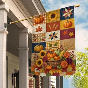 May include: A rectangular garden flag featuring a patchwork design with autumn motifs including pumpkins, sunflowers, wheat stalks, and maple leaves. The flag displays a central woven basket filled with harvest produce and is mounted on a gold pole.
