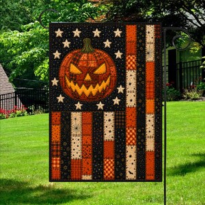 May include: A rectangular garden flag featuring a patchwork design in black, orange, and cream. The upper left section displays a large jack-o'-lantern with a jagged grin surrounded by twelve stars. The remaining area consists of vertical stripes.