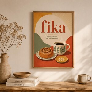 Pode incluir: Uma impressão artística emoldurada com a palavra fika em letras vermelhas grandes e o texto Coffee, pastries, and a short break. A ilustração mostra um rolo de canela num prato, uma caneca de café com padrões e um pires com uma flor.