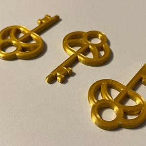 May include: Three gold-colored keys with intricate designs on the keyhole. The keys are made of a smooth, shiny material and have a slightly aged look.