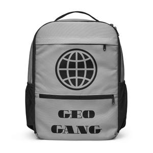May include: A light gray backpack featuring a black globe icon centered on the upper front pocket and the text "GEO GANG" printed in black lettering below. The bag includes black side mesh pockets, black zippers, and a black top handle.