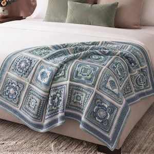 Könnte beinhalten: Eine Häkeldecke mit einem sich wiederholenden Muster aus quadratischen Motiven in Blau-, Petrol- und Weißtönen. Die Decke besteht aus einzelnen, miteinander verbundenen Quadraten, die jeweils komplexe florale und geometrische Texturen zeigen.