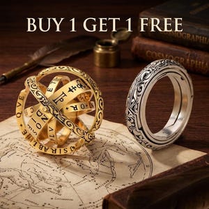Puede incluir: Un anillo de esfera armilar astronómica en tono dorado con letras y símbolos grabados, junto a un anillo en tono plateado con intrincados patrones de volutas. El texto BUY 1 GET 1 FREE es visible en la parte superior.